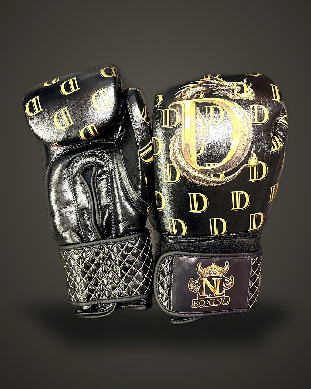 Dragon Monogram sponsorship boxing gloves — black leather with all-over gold D monogram and hand-finished gold dragon crest, New Level Boxing